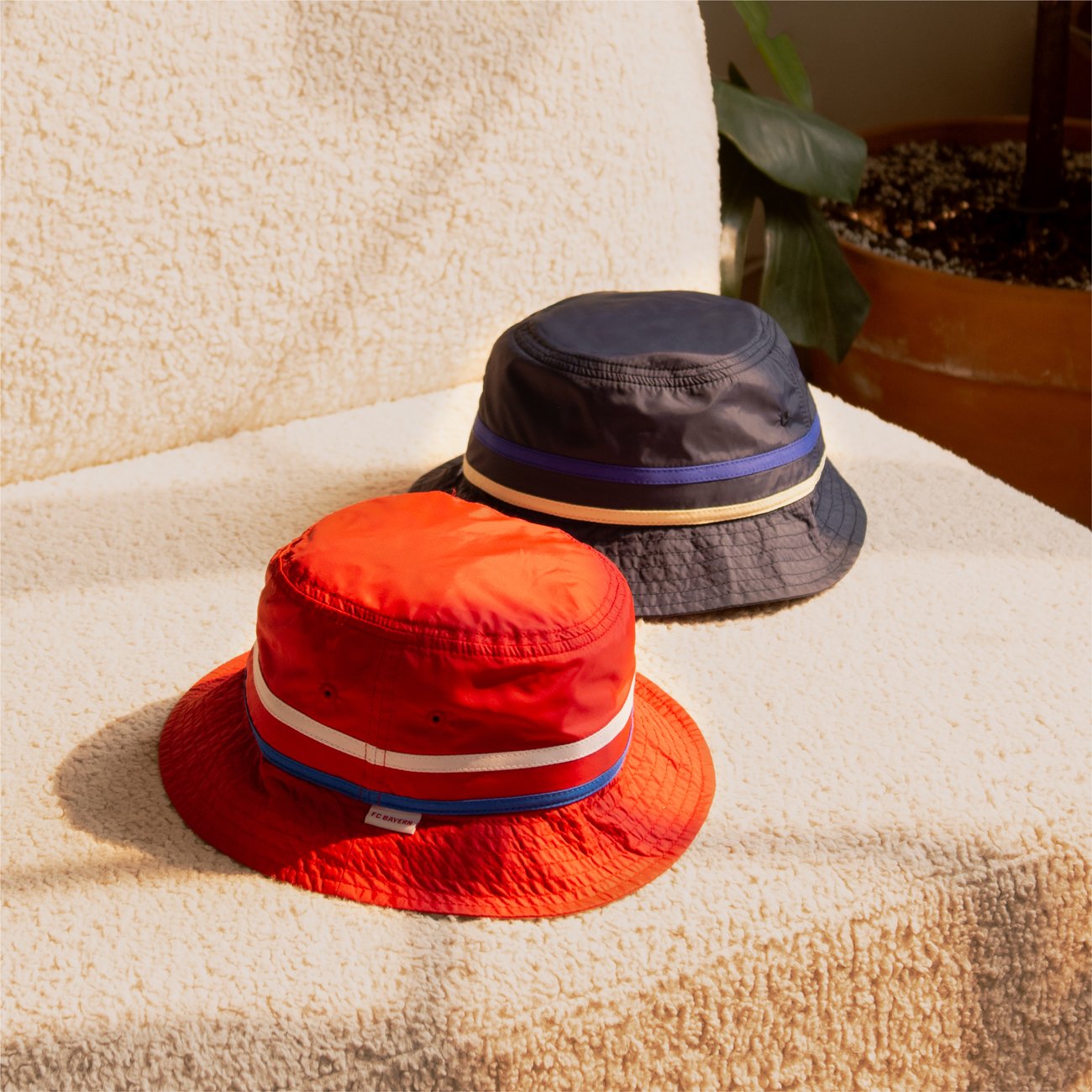 Two nylon bucket hats with woven ribbon bands, in daylight