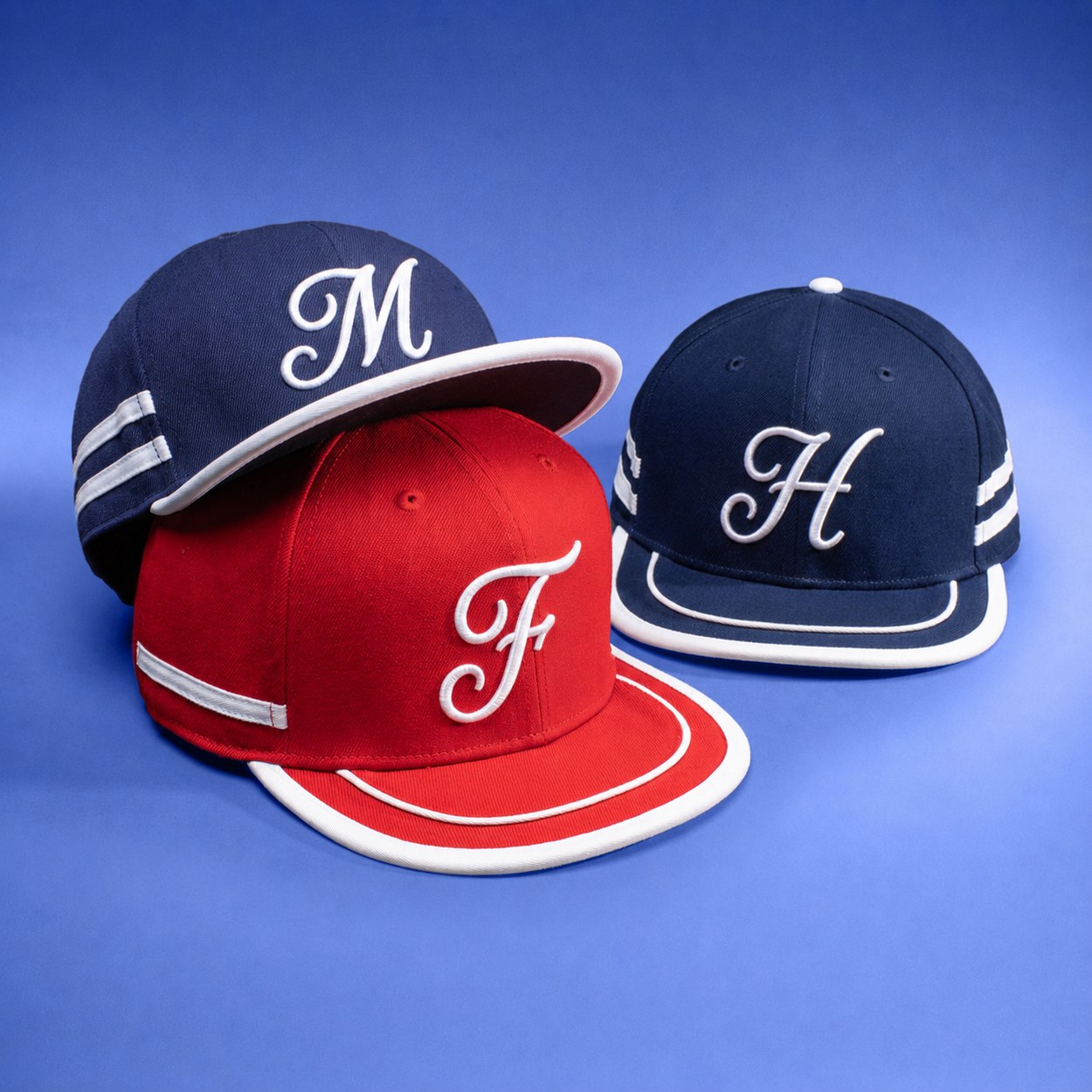 Three wool caps embroidered with the letters M, F and H in raised white script